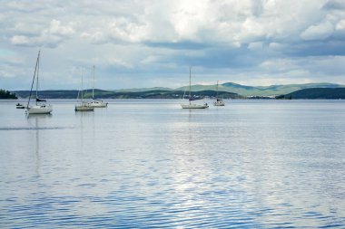 Rusya 'nın güneyindeki Urallar' da Turgoyak Gölü 'nde üç tekne yüzüyor. Biri kırmızı, biri beyaz, ve biri mavi.