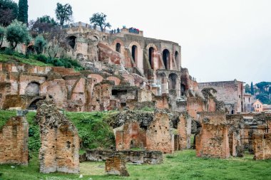 Roma 'da, önünde bir sürü tuğla ve çimenlik alan olan büyük bir bina. Bölgede dolaşan bir sürü insan var.