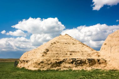 Arkaim, Rusya 'nın güney Urallar' ında antik bir yerleşim yeri. Bir tarlanın ortasında üç küçük ev var. Evlerin önünde duran iki kişi var.