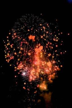 Gökyüzünde havai fişek gösterisi. Havai fişekler kırmızı ve beyaz. Gökyüzü koyu mavi