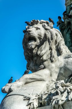 Milano İtalya 'da ağzı açık bir aslan heykeli ve üzerine kuşlar tünemiş. Kuşlar siyah ve beyaz.
