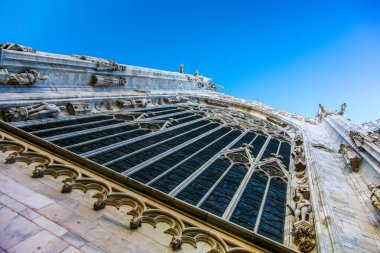 Arka planda mavi gökyüzü olan bir bina. Binanın bir sürü penceresi ve bir sürü detayı var.
