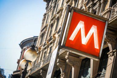 Milan İtalya 'daki metro tabelası. Üzerinde M harfi olan kırmızı beyaz bir tabela. Tabela bir direğe asılı.