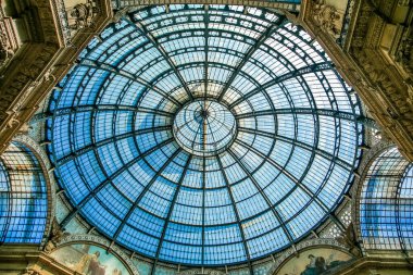 Milano İtalya 'sında üzerinde mavi gökyüzü olan büyük bir kubbe. Kubbe camdan yapılmış. Arka planda birkaç kişi var.