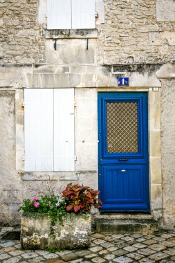 Konyak Fransa 'sında mavi işaretli mavi bir kapı. Kapı beyaz kapılı bir binanın üstünde.