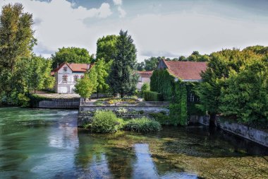 Kırmızı çatılı bir ev nehir kıyısında The Porte Saint-Jacques Quai Maurice Hennessy Konyağı 'nda bulunur. Ev ağaçlar ve çalılarla çevrili.