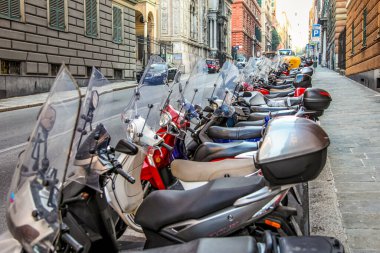 Mobiletler, İtalya 'nın Cenova kentinde bir cadde boyunca dizildi. Evler ve yollar görülebilir..