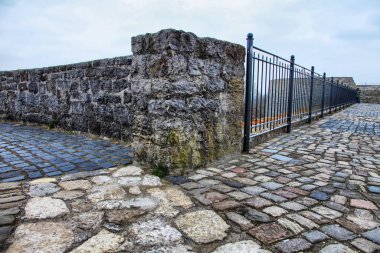 Ortasında kapı olan taş bir duvar. Kapı metalden yapılmış.