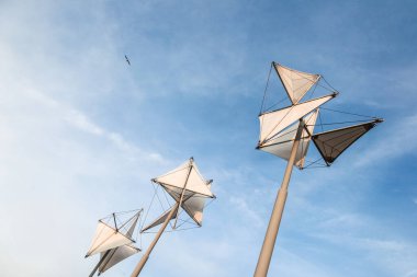 Cenova İtalya 'sında gökyüzünde üçgen şekilli üç beyaz yapı ayakta duruyor. Üzerlerinde bir kuş uçuyor.