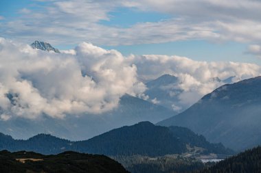 San Bernardino Geçidi 'nden geçen dolambaçlı bir yolu olan bir dağ sırası. Yol ağaçlar ve otlarla çevrili.
