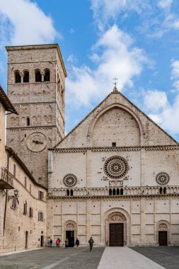 İtalya 'nın Umbria şehrinde Assisi şehrinde büyük bir kulesi ve küçük bir kulesi olan bir kale. Kale ağaçlarla çevrilidir. Gökyüzü bulutlu.