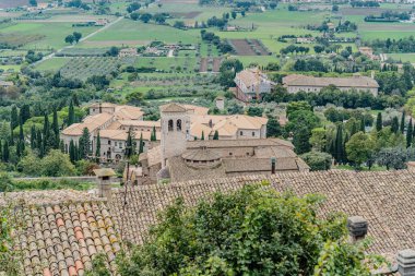 İtalya 'nın Assisi şehrinde birçok evi ve büyük bir tepesi olan bir şehir manzarası Umbria. Evlerin hepsi farklı boyutlarda ve yayılmış durumda.