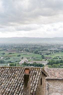 İtalya 'nın Assisi şehrinde birçok evi ve büyük bir tepesi olan bir şehir manzarası Umbria. Evlerin hepsi farklı boyutlarda ve yayılmış durumda.