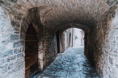 Gubbio İtalya Umbria 'nın solunda kapısı olan dar taştan bir tünel. Tünelin ortasında dikilen biri var.
