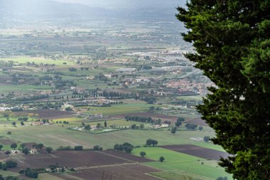 Gubbio Bakış açısı İtalya Umbria 'da birkaç evi olan büyük bir tarla. Gökyüzü bulutlu. Gubbio İtalya 'da uzakta küçük bir kasaba var Umbria
