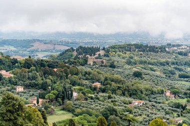 İtalya 'da Perugia Umbria' da evleri ve ağaçları olan bir yamaç. Evler kahverengi ve beyaz. Ağaçlar yeşil.