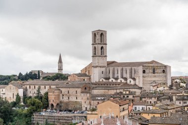 Ortada büyük bir bina bulunan Perugia İtalya 'nın Umbria kenti. Binanın saat kulesi var. Şehirde bir sürü bina var.