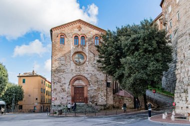 İtalya 'da Perugia Umbria' da saati olan büyük bir bina. Bina ağaçlarla çevrili. Bölgede dolaşan insanlar var.
