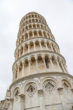 Pisa İtalya Toscana 'nın tepesinde saati olan uzun beyaz bir kule. Kule bir sürü insanın olduğu bir şehirde.