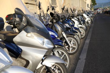 Floransa İtalya Toscana 'da yolun kenarına bir sıra motosiklet park edilmiş. Motosikletler siyah, gümüş ve mavi de dahil olmak üzere çeşitli boyutlarda ve renklerdedir. Organizasyon ve düzen kavramı