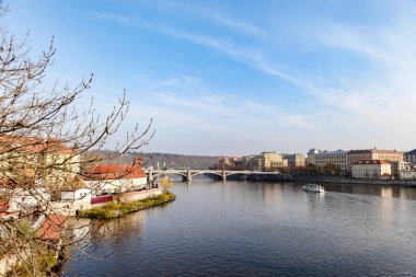 Çek Cumhuriyeti 'nin Prag şehrinde Vltava nehri üzerinde köprü bulunan bir nehirden geçer. Su sakin ve gökyüzü berrak.