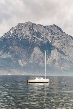 Traunsee Avusturya 'daki bir dağ gölünün önündeki rıhtıma bir tekne yanaştı. Gökyüzü bulutlu ve su sakin.