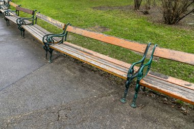 Kaldırıma dizilmiş eski ahşap banklar var. Banklar boş ve tamir edilmesi gerekiyor gibi görünüyor. Sahne ihmal ve terk edilme hissi veriyor.