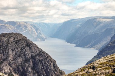 Norveç 'teki dağlarda Preikestolen' e giden patikalar, fiyordu gökyüzü bulutludur. Dağlar çok yüksek ve su çok derin..