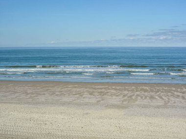 Kumsal boş ve Almanya 'da deniz sakin. Gökyüzü mavi ve güneş parlıyor.