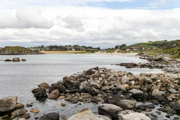 Norveç 'in arka planında bir su kütlesi olan kayalık bir kıyı şeridi. Su sakin ve kayalar kıyı boyunca dağılmış. Sahnenin huzurlu ve huzurlu bir atmosferi var.