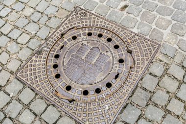 Üzerinde Hamburg yazan metal bir ızgara, Hanseatic City. Ortasında bir delik olan. Izgara kaldırımda kaldırım kenarında.