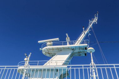 Yanında cankurtaran salı olan bir tekne. Cankurtaran salı beyaz ve tekneye bağlı. Tekne okyanusta ve gökyüzü mavi.