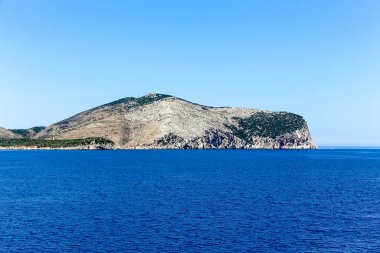 Sardunya Adası 'ndaki bir dağ mavi bir Akdeniz' in arka planındadır. Dağ ağaçlarla kaplıdır ve çok uzundur.