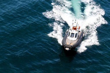 Bir tekne, Sardunya adası yakınlarında arkasında bir uyanışla denizde seyahat ediyor. Tekne siyah beyaz.