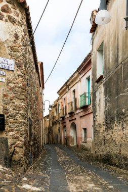 İtalya 'nın Orosei Adası' nda dar bir sokak. Sol tarafında mavi bir tabela var. Sokak eski binalarla dolu ve kaldırım taşı yolu var.
