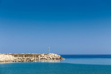 İtalya 'nın Sardunya adasında küçük bir deniz feneri olan kayalık bir kıyı şeridi. Su sakin ve gökyüzü berrak.