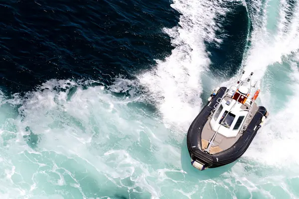 Bir tekne, Sardunya adası yakınlarında arkasında bir uyanışla denizde seyahat ediyor. Tekne siyah beyaz.