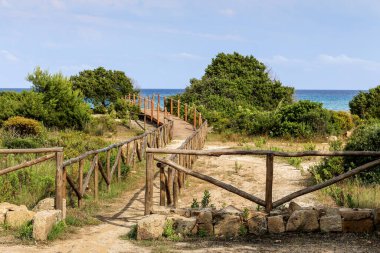 Tahta bir çit İtalya 'daki Sardunya adasındaki bir ormandan bir plajı ayırır. Çit ahşaptan yapılmıştır ve kırsal bir görünüme sahiptir. Plaj güzel, sakin bir yerdir. Arkasında berrak mavi bir okyanus vardır.