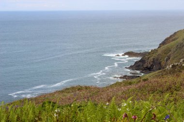 İngiltere 'nin tepesinde evi ve deniz feneri olan bir tepe. Ev beyaz ve deniz feneri uzun. Yamaç yemyeşil ve yemyeşil, ve arkada da okyanus var. Huzurlu ve huzurlu bir sahne.