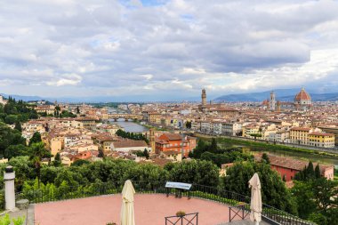 İtalya 'nın Floransa şehri Toscana' nın içinden bir nehir akan manzarası. Binalar eski ve kahverengi. Gökyüzü bulutlu.
