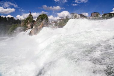 Gökyüzünde gökkuşağı olan Schaffhausen İsviçre 'de bir Ren şelalesi. Su beyaz ve gökyüzü mavi.