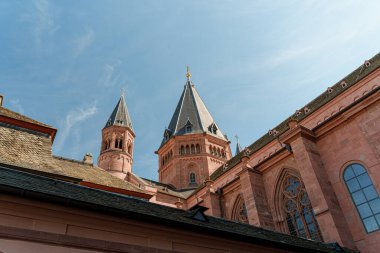 Mainz Almanya 'sında çan kulesi ve saat kulesi olan yüksek bir Dom St. Martin binası. Gökyüzü mavi ve berrak. Bina ağaçlarla çevrili.