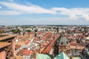 Tepesinde haç olan yüksek bir binayla Strasburg şehri manzarası. Şehir ağaçlar ve binalarla dolu.