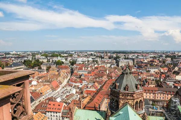 Tepesinde haç olan yüksek bir binayla Strasburg şehri manzarası. Şehir ağaçlar ve binalarla dolu.