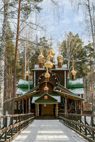 Yekaterenburg Rusya 'sında üzerinde altın kubbeler ve haç olan küçük tahta bir kilise. Kilise ağaçlar ve karlarla çevrili.
