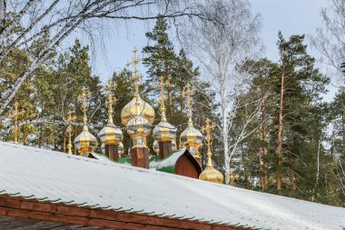 Bir grup altın ve gümüş haç bir binanın tepesinde. Haçlar farklı boyutlarda ve şekillerde ve hepsi aynı yöne bakıyor. Sahne saygı ve maneviyattır.
