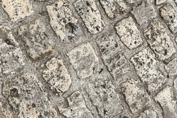 Bir tuğla kaldırıma yakın çekim ve bir sürü doku. Tuğlalar farklı boyutlarda ve şekillerde ve genel görünümü pürüzlü ve düzensiz.