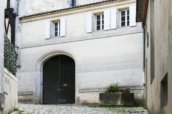 Beyaz binalı küçük bir avlu ve Konyak Fransa 'da siyah bir kapı. Kapı açık ve yerde bir saksı var.