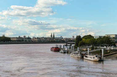 Bordeaux Fransa 'nın Goronne Nehri' nin bulutlu bir gününde bir grup tekne rıhtıma yanaştı. Su kahverengi ve gökyüzü bulutlu.