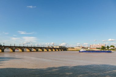 Bordeaux Fransa 'daki bir taş köprü arkasında bulutlu bir gökyüzü olan bir nehri kapsar. Köprü kırmızı tuğlalardan yapılmıştır ve suyla çevrilidir.